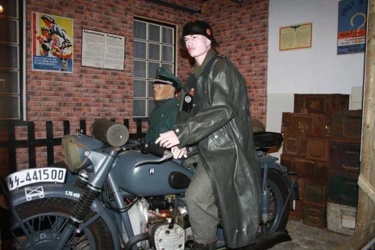 Twee mannequins in Duitse WOII‑uniformen op een motorfiets in een museum.