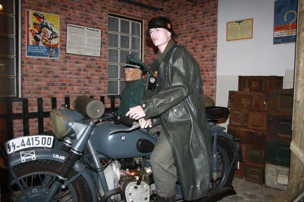 Twee mannequins in Duitse WOII‑uniformen op een motorfiets in een museum.