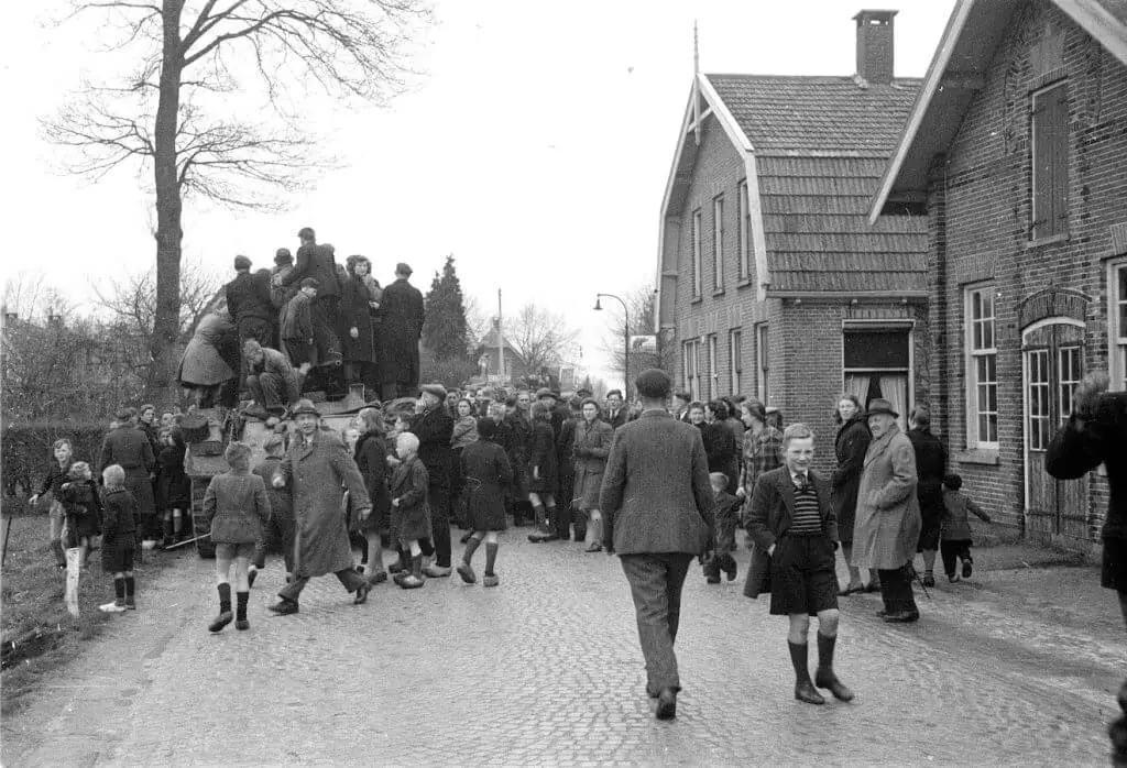Zwart-witfoto van een feestelijke menigte in Vriezenveen die de bevrijding door tanks op 5 april 1945 viert.